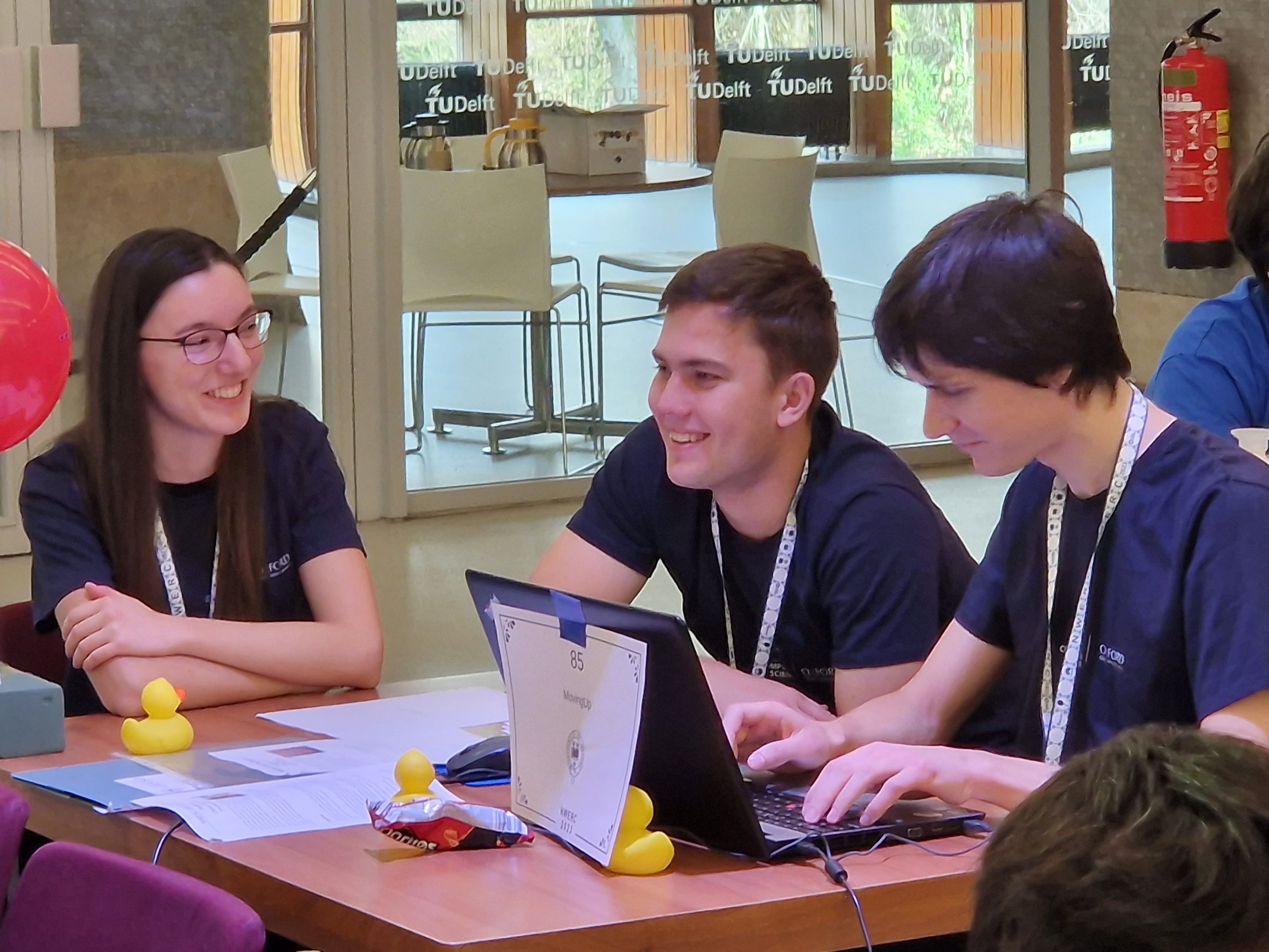 Team MovinUp mid-way through the competition. Three team members are sat around a computer solving problems