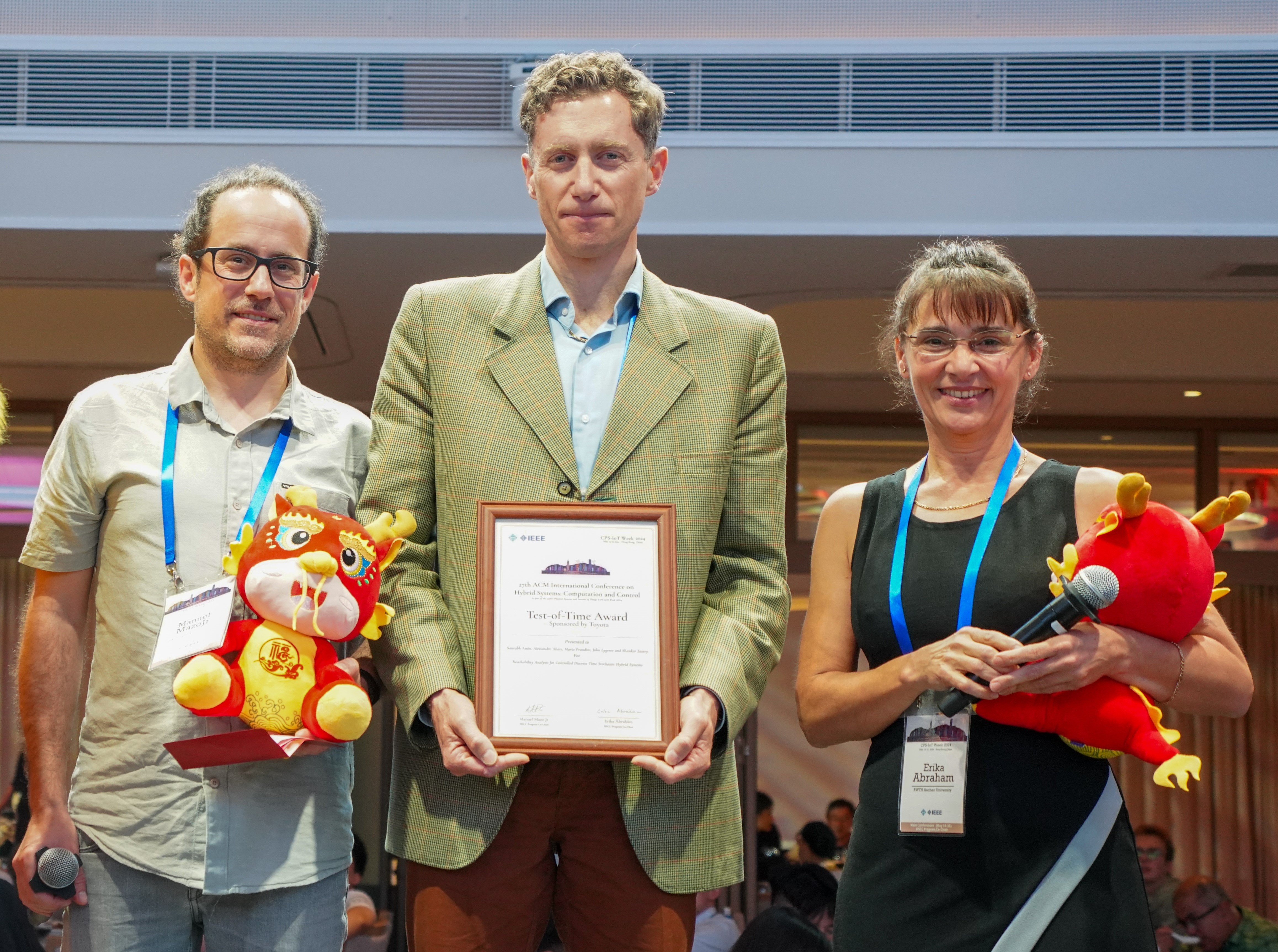 Image showing Professor Alessandro Abate holding the HSCC award, with conference Chairs Manuel Mazo Jr (left) and Erika Abraham (right)